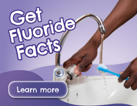 A person's hands rinsing a toothbrush under water in a sink