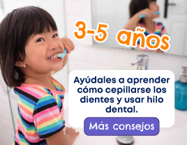 Una niña sonriente cepillándose los dientes frente al espejo.